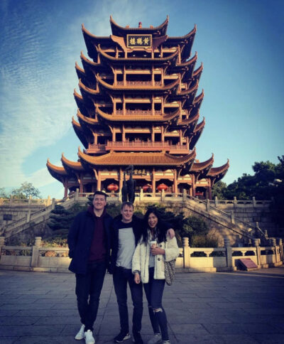 Three people standing in front of Yellow Crane Tower in Wuhan, China
