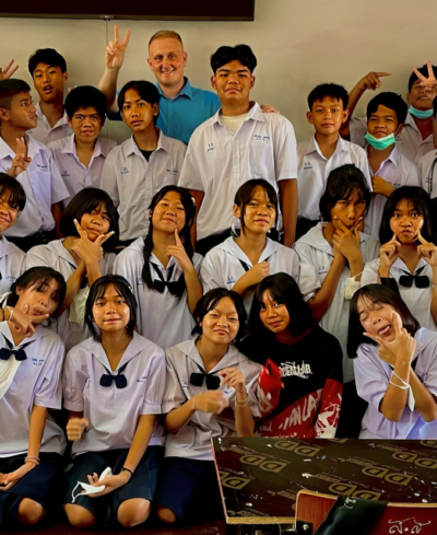 male English teacher surrounded by a big group of Thai high school students 