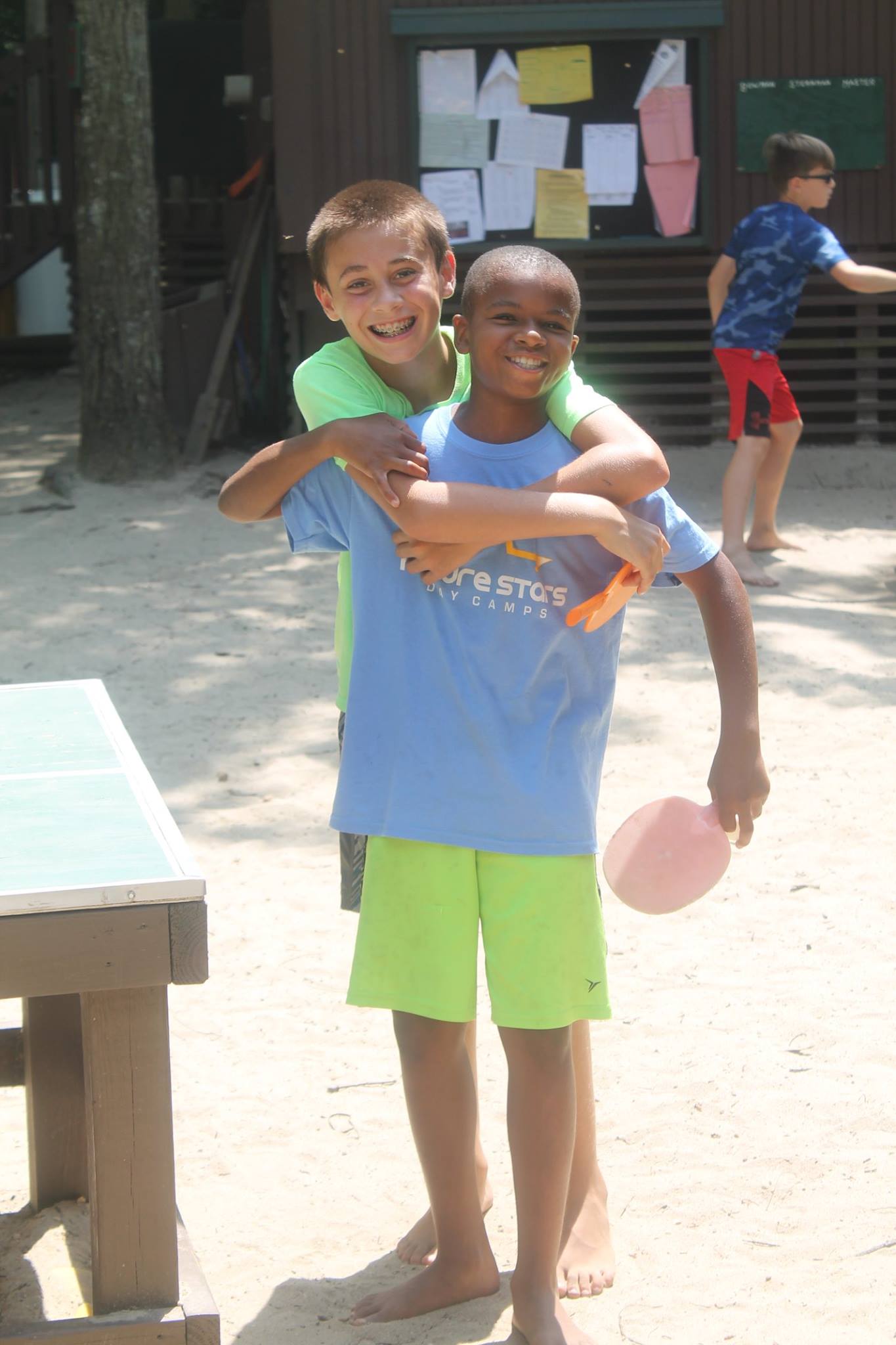 Two young boys hugging and smiling at a summer camp in the USA