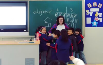 Teacher hugging at the blackboard with her students 