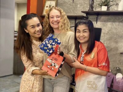 Three smiling women holding up a bag 