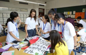 Group of students and an English teachers in China looking at a calligraphy work in the middle of the table 
