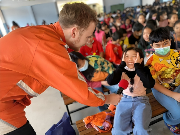 Teacher handing a microphone to a young student in Thailand 