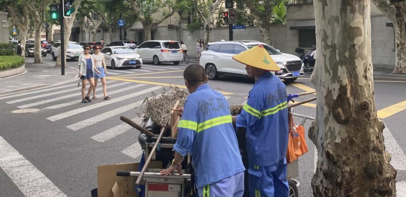 streets of Shanghai, with a street cleaner crossing the road 