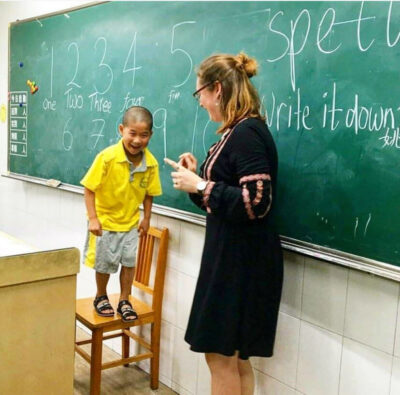 Smiling child in China with his English teacher