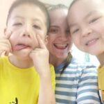 Smiling teacher in China with her students, who are also smiling